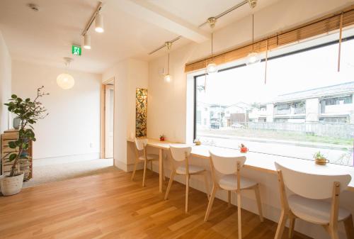 a dining room with a table and chairs and a large window at Mulan Hostel in Kyoto