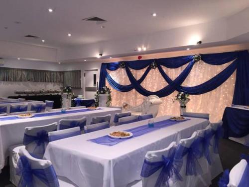 a banquet hall with white tables and blue chairs at Manukau Hotel & Conference Centre in Auckland