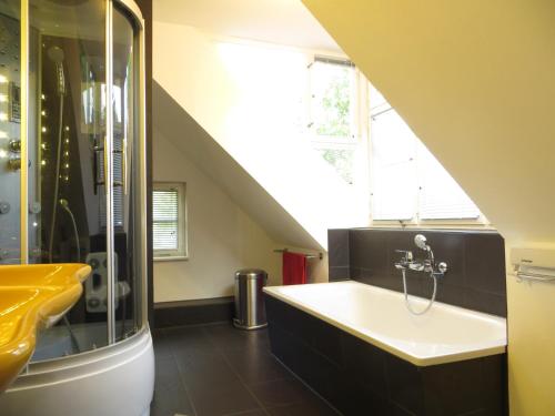uma casa de banho com um chuveiro e uma banheira com um lavatório. em Fischerhaus am See em Berlim