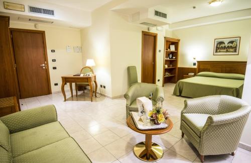 a hotel room with a bed and a couch and chairs at Grand Hotel Victoria in Bagnara Calabra