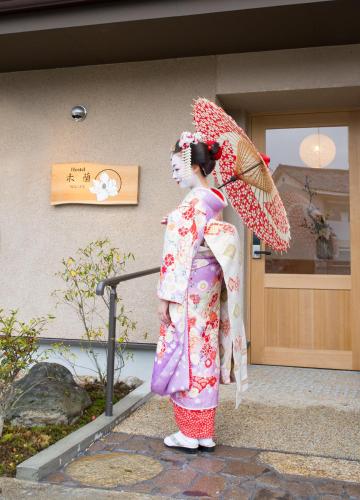 a woman in a kimono holding an umbrella at Mulan Hostel in Kyoto