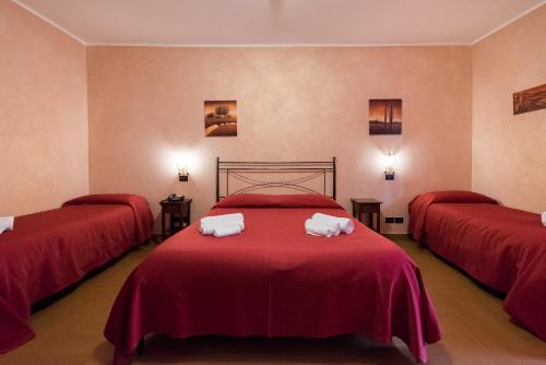 Habitación con 3 camas y sábanas rojas. en Valle Himara, en Piana degli Albanesi