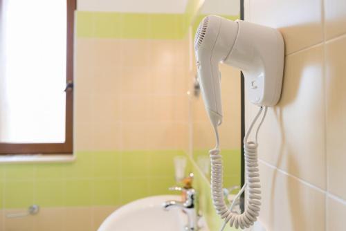 a white hairdryer hanging on a wall in a bathroom at Valle Himara in Piana degli Albanesi