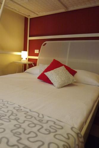 a bed with a red and white pillow on it at B&B Il Tempo Del Vento in front of the Castle in Tresana
