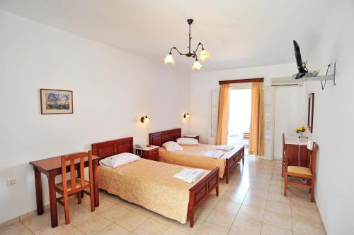 1 dormitorio con 2 camas, mesa y sillas en Karkisia Hotel, en Egíali