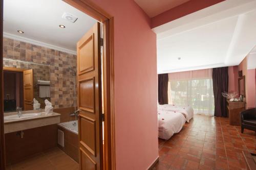 a bedroom with a bed and a bathroom with a sink at Hotel Dar Eddaya in Khemisset