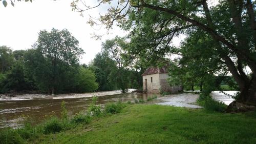an old building sitting on the side of a river at Moulin d'Amour in Chambon