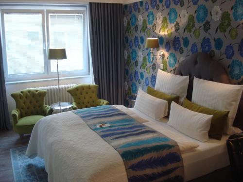 a bedroom with a large bed and two chairs at Hotel Sir & Lady Astor in Düsseldorf