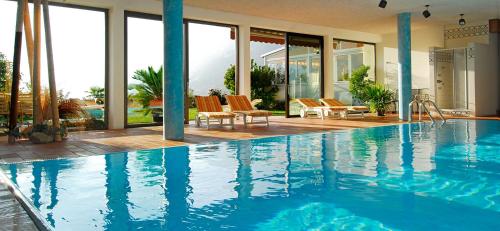 a large swimming pool with chairs and a house at Pension Grafenau in Schenna