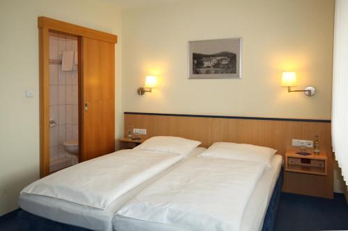 Hotel garni Zum Drosten في Balve: غرفة نوم بسريرين بيض وحمام