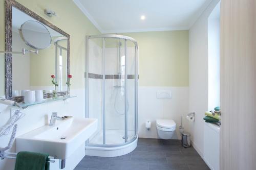 a white bathroom with a shower and a sink at Pension Kalinde in Weinböhla