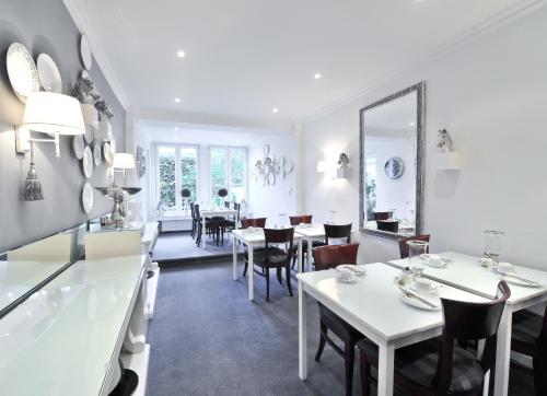 a dining room with white tables and chairs at Hotel Sir & Lady Astor in Düsseldorf