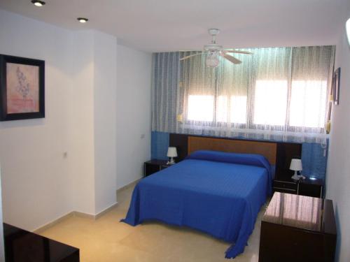 a bedroom with a blue bed and two windows at Gemelos 11 - Fincas Arena in Benidorm