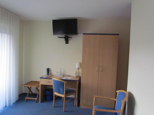 Zimmer mit einem Schreibtisch, Stühlen und einem Schrank in der Unterkunft Hotel garni Zum Drosten in Balve