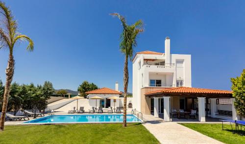 a large white house with a swimming pool and palm trees at Gennadi Beach Villas - Waterfront Luxury Retreat with Private Beach in Gennadi