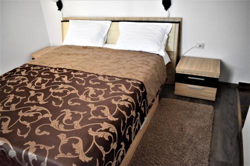 1 dormitorio con 1 cama con manta marrón y almohadas blancas en Pensiunea Alexandra, en Corbii Mari