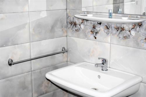 Baño blanco con lavabo y espejo en Pensiunea Alexandra, en Corbii Mari