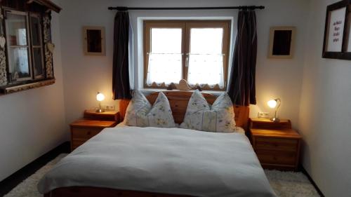 a bedroom with a bed with a window and two lamps at Haus am Sunnfeld in Alpbach