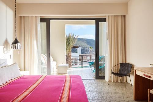 a bedroom with a pink bed and a balcony at Hotel San Cristobal Adults 15+ in Todos Santos