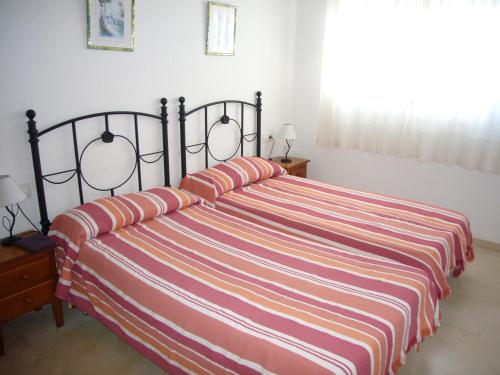 a bedroom with a bed with a striped blanket at Gemelos 22 - Fincas Arena in Benidorm