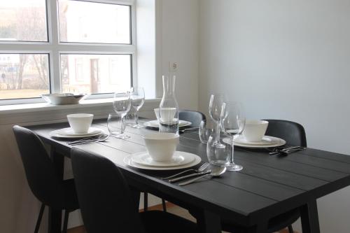 a black table with chairs and wine glasses on it at Askja Apartment in Húsavík
