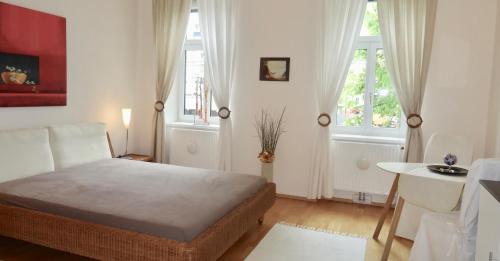 a bedroom with a bed and a table and two windows at Sonnberg Apartments in Vienna