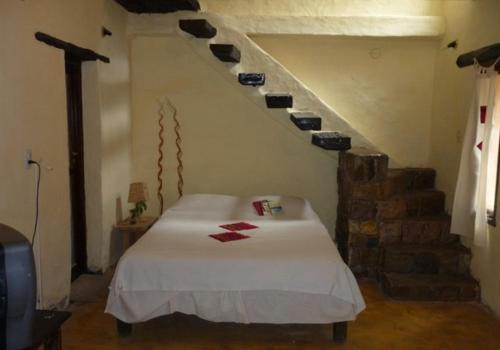 a room with a bed and a staircase with shoes on the wall at Piedramora Tilcara in Tilcara