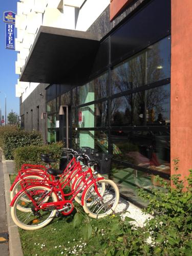 a group of red bikes parked in front of a building at Best Western Plus Paris Velizy in Vélizy-Villacoublay