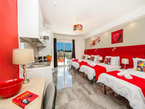 a room with four beds with red and white sheets at Bayside Apartments in St Julian's