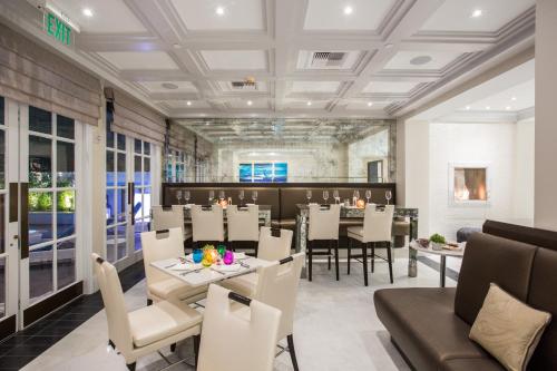 um restaurante com mesas e cadeiras brancas e uma sala de jantar em Mosaic Hotel Beverly Hills em Los Angeles