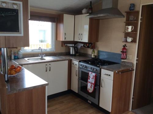 a small kitchen with a stove and a sink at Warren Retreat in Dawlish