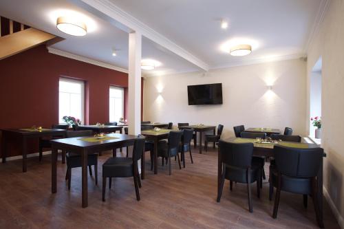 a dining room with tables and chairs and a flat screen tv at Pension Kalinde in Weinböhla