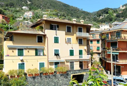 Sivori Apartment في بوناسولا: مبنى أصفر كبير مع نوافذ خضراء على جبل