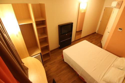 a small room with a bed and a television at Samba Itaboraí in Itaboraí