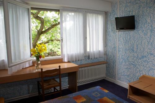 a room with a table and a window with a vase of flowers at Hôtel Le Lyon Bron in Bron