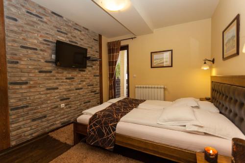 1 dormitorio con cama y pared de ladrillo en Guest House Vila Bajka, en Zlatibor