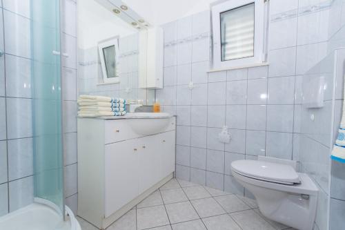 a white bathroom with a toilet and a sink at Villa Snježana in Trogir