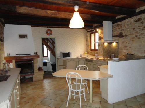 une cuisine avec une table et des chaises ainsi qu'une cheminée dans l'établissement Gite De Rouffiac, à Saint-Cirq-Madelon