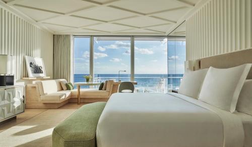 - une chambre avec un grand lit blanc et une vue sur l'océan dans l'établissement Four Seasons Hotel at The Surf Club, à Miami Beach