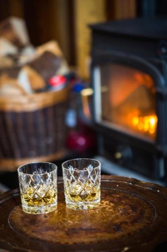 two glasses of whiskey on a table in front of a fireplace at Cruickshanks Boutique B&B in Whiting Bay