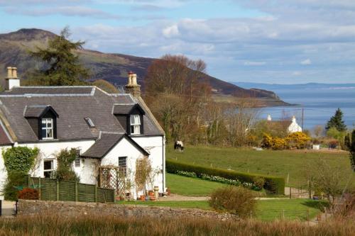 a house in a field with a view of the water at Cruickshanks Boutique B&B in Whiting Bay