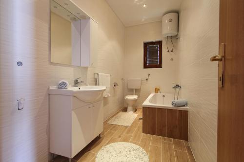 een badkamer met een wastafel, een toilet en een bad bij Apartments&Room Babic in Kaštela