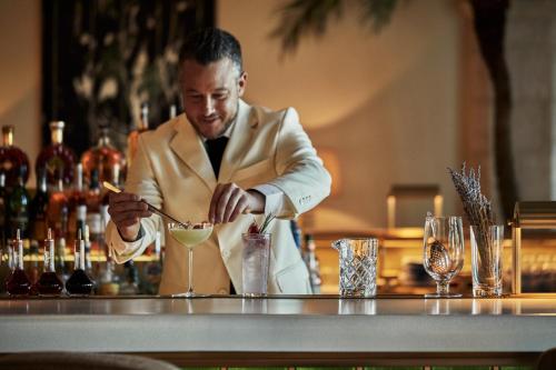 a man in a suit preparing a drink at a bar at Four Seasons Hotel at The Surf Club in Miami Beach