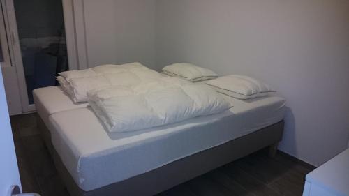 a bed with white sheets and pillows on it at lounge appartement zeedijk Oostende in Ostend