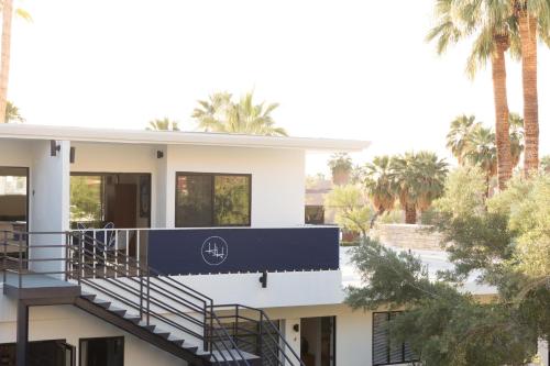 a white house with a balcony with palm trees at Holiday House Palm Springs in Palm Springs