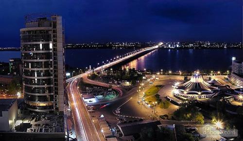 a view of a city at night with a bridge at Most City Apartments Magnolia in Dnipro