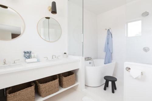 a white bathroom with a sink and a mirror at Holiday House Palm Springs in Palm Springs