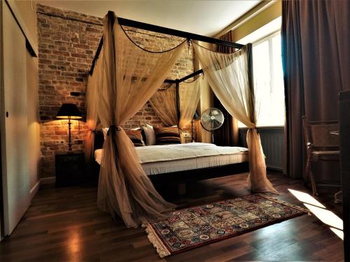 a bedroom with a canopy bed with curtains and a rug at SLEEPWELL NOWY ŚWIAT - wejście przez dziedziniec - brama Ordynacka 14 in Warsaw