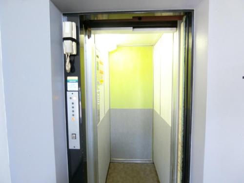 a hallway with a door leading to an elevator at Simple Stay Beppu in Beppu