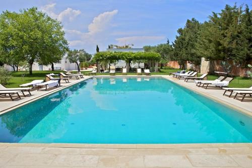 a large swimming pool with lounge chairs at Masseria Montelauro in Otranto